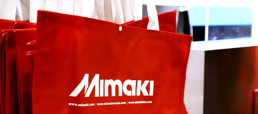 Red tote bag with the Mimaki logo printed on it