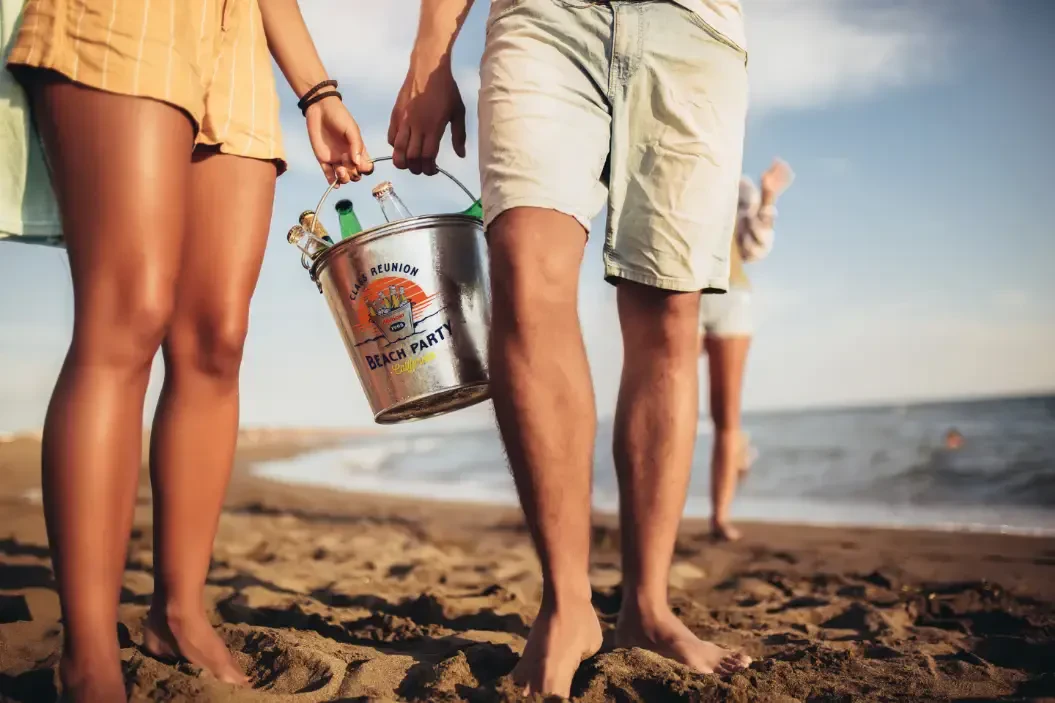Man and woman holding a bucket with a beach party graphic on it