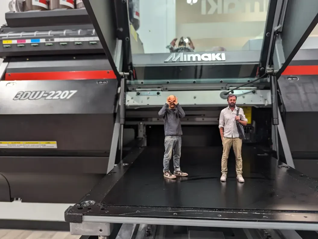 Image of two people standing on a 3d printer